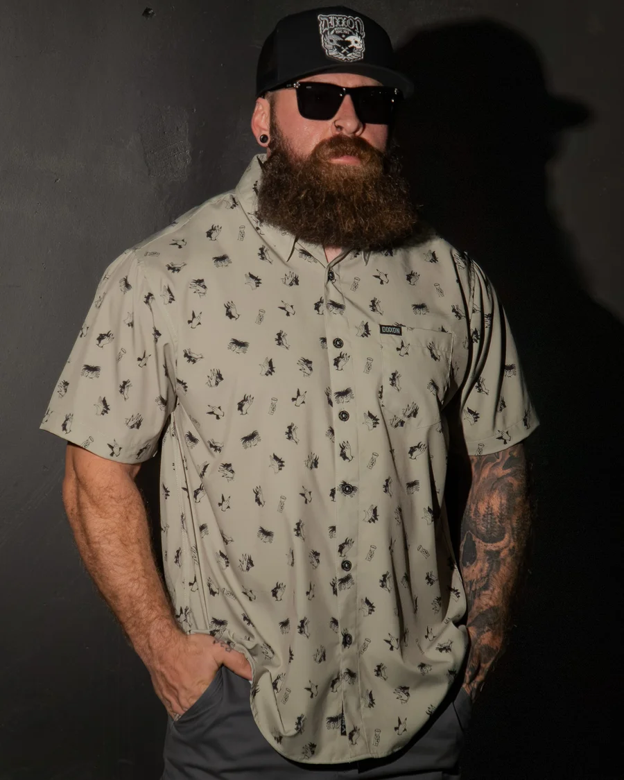 Unhinged Party Shirt, cream with black illustrated print, worn by a bearded man in a cap.